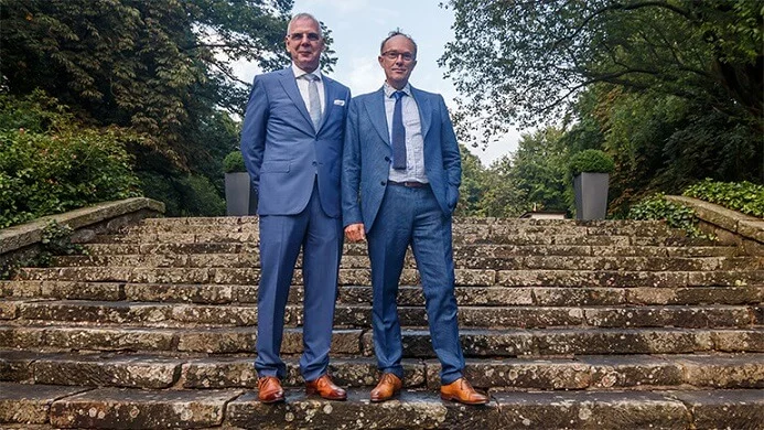 Zwei Kollegen besprechen sich auf den Steinstufen im Grünen - bereit für ihren nächsten Einsatz auf der Baustelle.